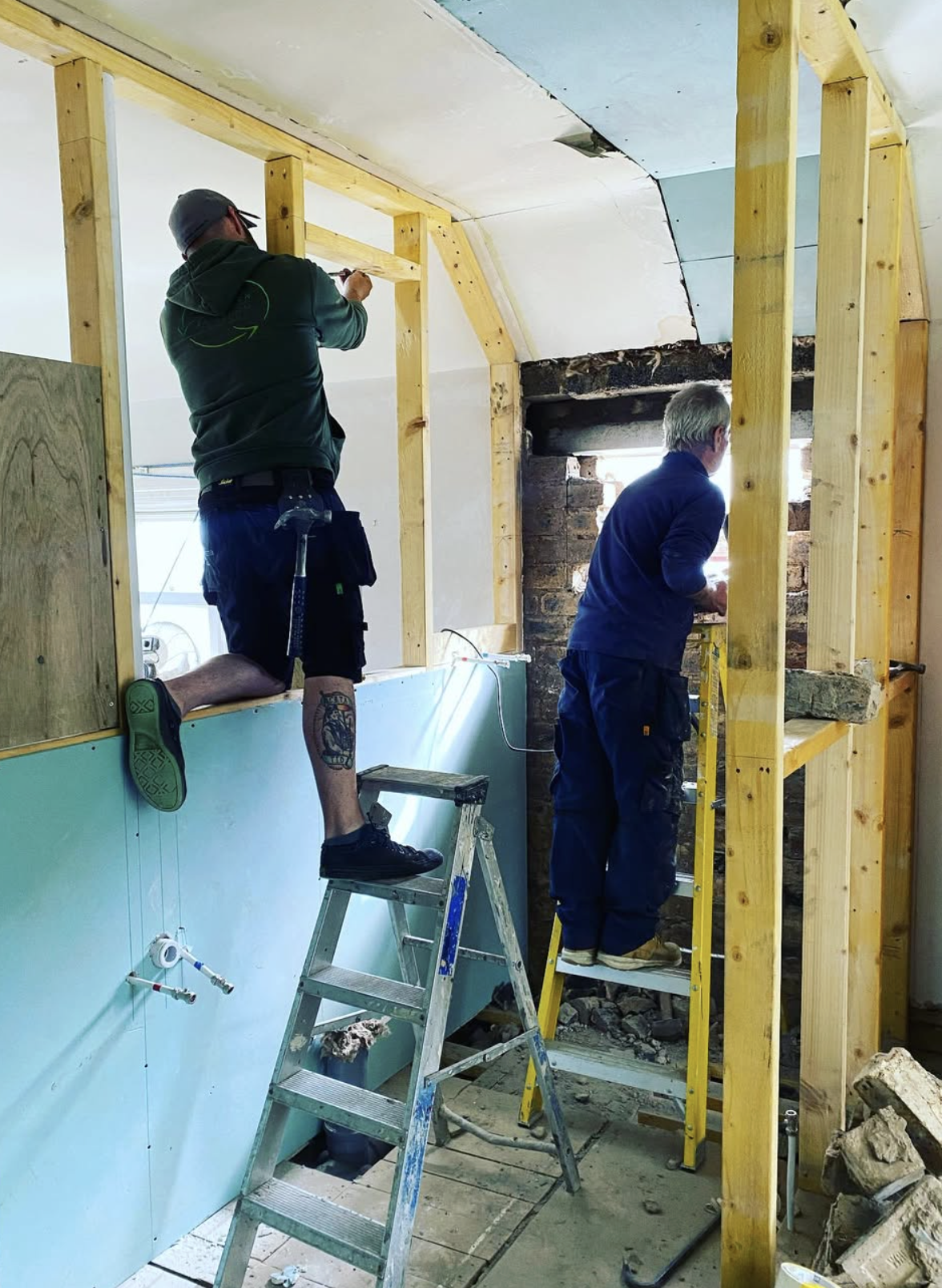 Two tradespeople working on a bathroom renovation in progress
